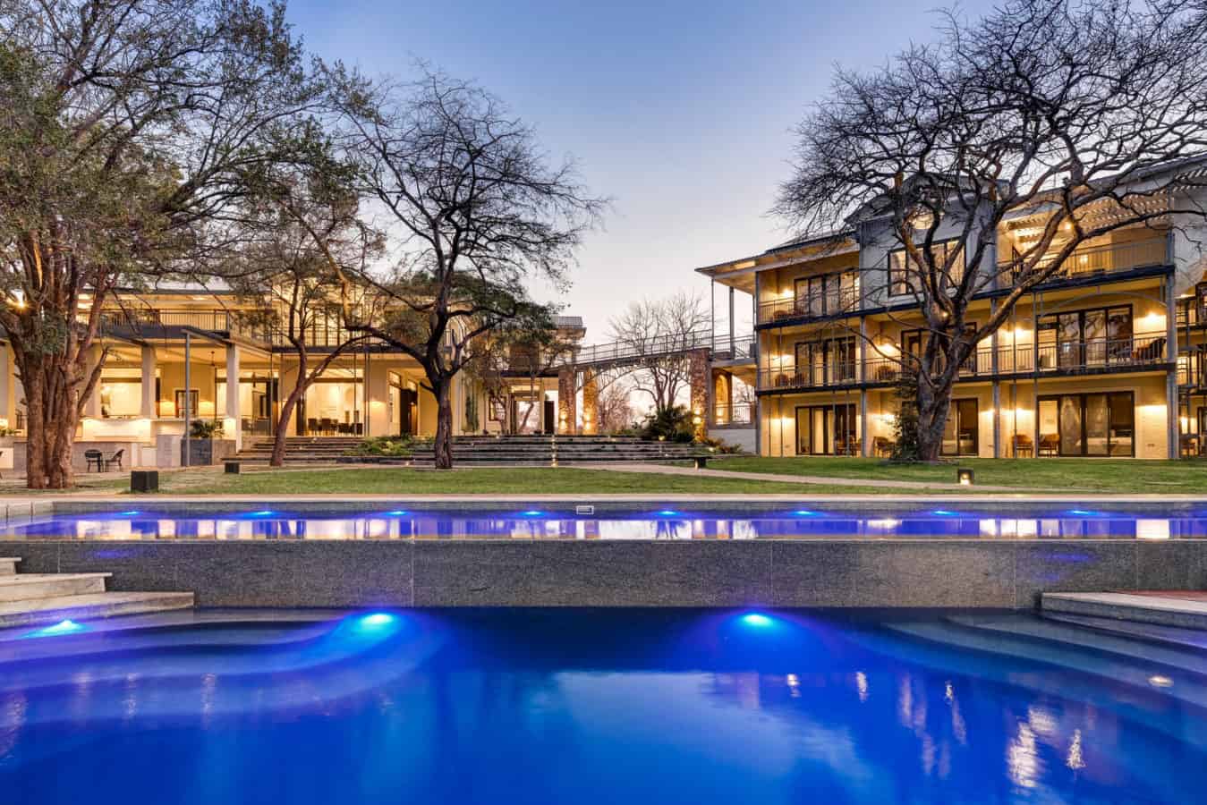 Riverside hotel exterior with pool at dusk